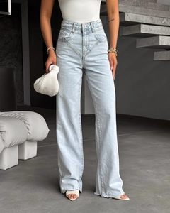 Détail d'un jean évasé taille haute bleu clair avec ourlet vieilli sur un mannequin femme