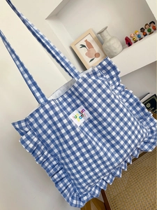 Detail of blue and white checkered tote bag with ruffle trim and fun fun party label