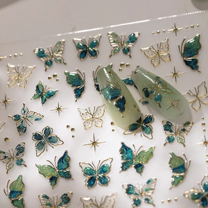 Sparkling blue-green butterfly nail stickers with gold accents on light green nails