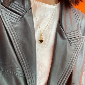 Detail of a gold heart pendant necklace with black inlay on a delicate bead chain