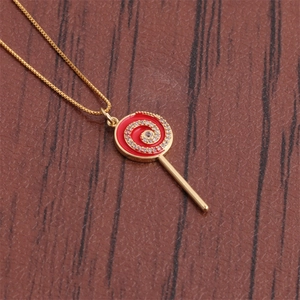 Gros plan d'un collier doré avec pendentif sucette en émail rouge et cristaux brillants