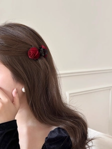 Detail view of a vintage dark red velvet rose hair claw clip worn on wavy brown hair
