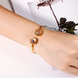 Detail of gold open bangle featuring square champagne crystals worn on a wrist