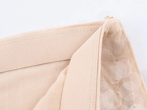 Dettaglio del tessuto a rete con paillettes beige e fascia elastica ad alta tenuta