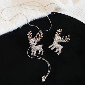 Macro detail of silver reindeer necklace and brooch set with sparkling rhinestones