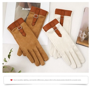 Close-up of suede winter gloves with metallic buckle and leather trim details