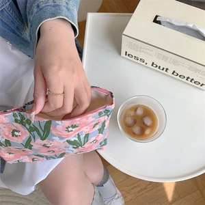 Close-up of floral cotton pouch held by a model in a natural afternoon tea setting