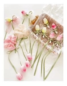 Detailed close-up of realistic silk tulip flowers and ribbon bow hair clips on lace cloth