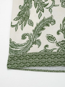 Detailed close-up of linen fabric texture with vintage green floral print on long sleeve shirt