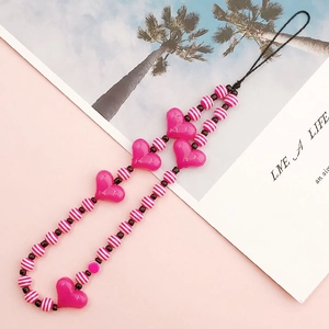 Close-up of pink acrylic heart charms and striped beads on a sweet style phone strap