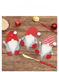 Close-up of three festive Christmas gnome silverware holders on a rustic wooden table