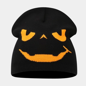 Close-up of the orange pumpkin face jacquard pattern on black knitted winter beanie