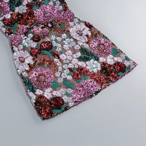 Détail de broderies florales à paillettes complexes sur le tissu d'une robe de luxe