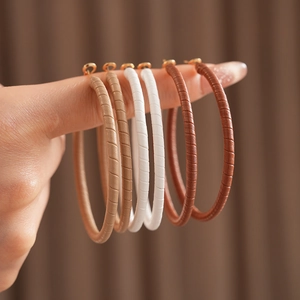 Macro shot of large hoop earrings wrapped in khaki, beige, white, and brown faux leather