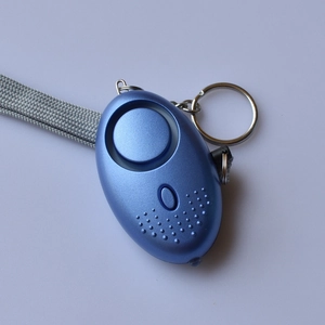 Detail of light blue personal alarm with metallic finish, speaker grille, and gray lanyard