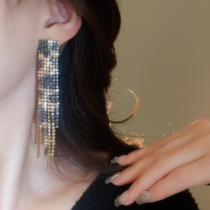 Close-up of dangling tassel earrings with gold and black rhinestones worn by a model