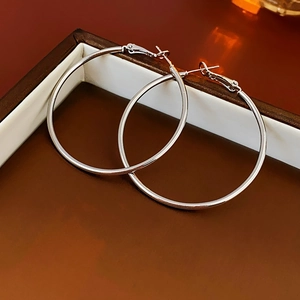 Macro view of polished silver metal hoop earrings displayed in a dark brown jewelry box