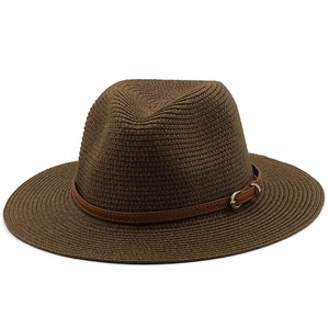 Close-up of woven straw sun hat with brown leather band and golden metal buckle detail