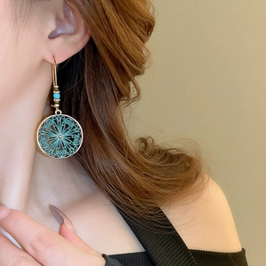 Close-up of bohemian hollow flower earrings with antique gold and turquoise detail