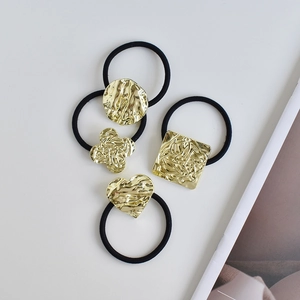 Close-up of four ponytail holders with gold hammered metal charms in geometric shapes