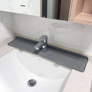 Detailed view of a grey silicone faucet draining mat on a bathroom sink with water ripples