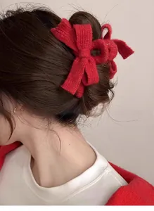 Detail of red knitted bow hair claw clip styled on back of head with a half-up hairstyle