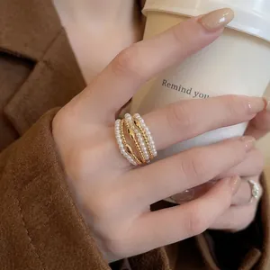 Elegant multi-layer gold plated ring with pearls shown on hand holding a coffee cup