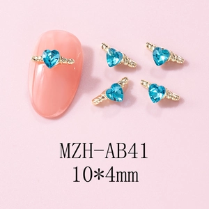 Macro detail of sky blue heart crystal nail charms with gold twisted metal frame MZH-AB41