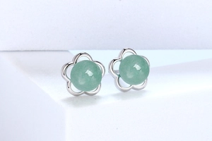 Detail view of flower-shaped silver earrings with a green aventurine gemstone center