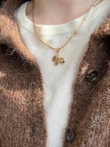 Detail of gold plated necklace with a colorful gemstone pony pendant on model neck
