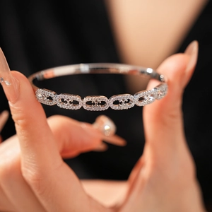 Macro shot of silver bangle with cubic zirconia pavé links and central C-motif detail