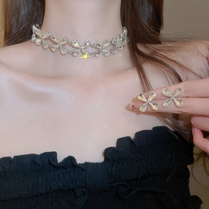 Macro shot of silver four-leaf clover jewelry set featuring crystals on model
