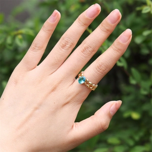 Gros plan d'une bague dorée avec pierre bleue et anneau perlé double sur la main