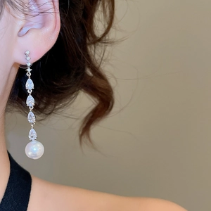 Macro shot of silver tassel earrings with zircon water drops and white round pearls