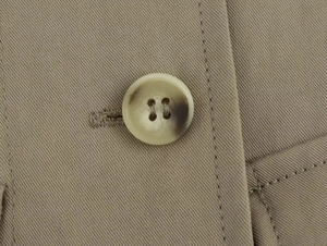 Dettaglio macro di bottone marmorizzato e trama in tessuto twill su abito corto kaki