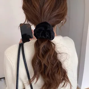 Dettaglio di un elastico per capelli in velluto nero su una coda di cavallo bassa