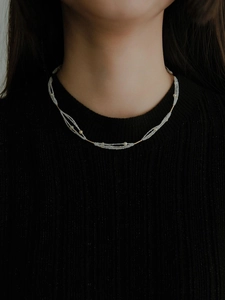Close-up of layered white seed bead necklace with gold accents on a black knit top