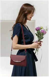 Red crossbody bag with pebble grain leather texture shown on a female model