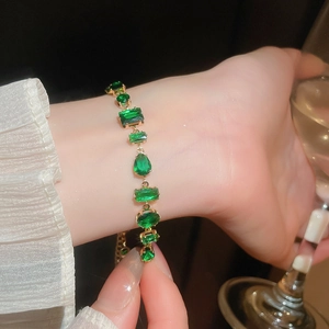 Detailed view of irregular emerald zircon bracelet with gold-plated geometric charms