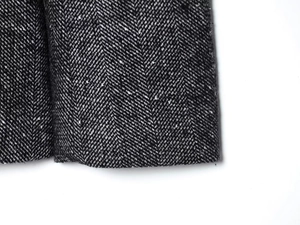 Vista macro della classica trama del tessuto tweed a spina di pesce nero e grigio