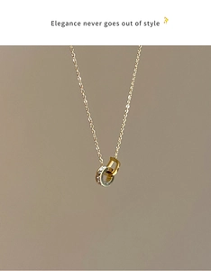 Détail d'un collier en titane doré avec pendentif lettre D et doubles anneaux en zircon