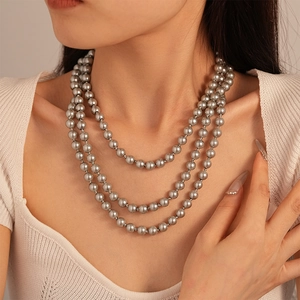 Detail of vintage three-layer dark grey pearl necklace on a white knit sweater