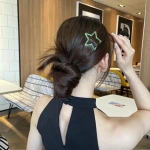 Close-up of a vibrant green star-shaped hair clip securing a stylish bun hairstyle