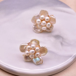 Elegant natural pearl flower earrings with golden metal base on white marble background