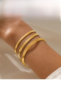 Detailed view of three layered gold flat snake chains on wrist with high polish finish