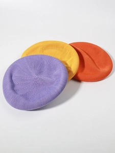 Detail view of purple, yellow, and orange knitted linen beret hats with textured finish