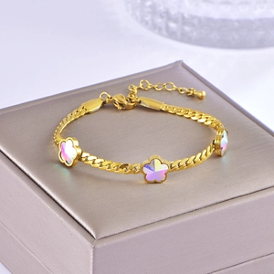 Detailed shot of golden snake chain bracelet with opal-style floral charms on jewelry box