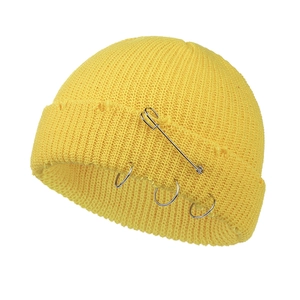 Detail showing the bright yellow knit beanie with metallic rings and decorative pin