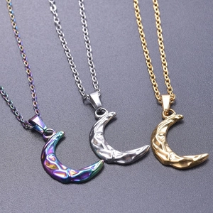 Three moon pendants in gold, silver and rainbow colors on textured grey background