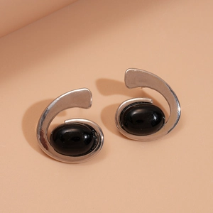 Detailed macro view of abstract silver-toned spiral earrings with oval black stones